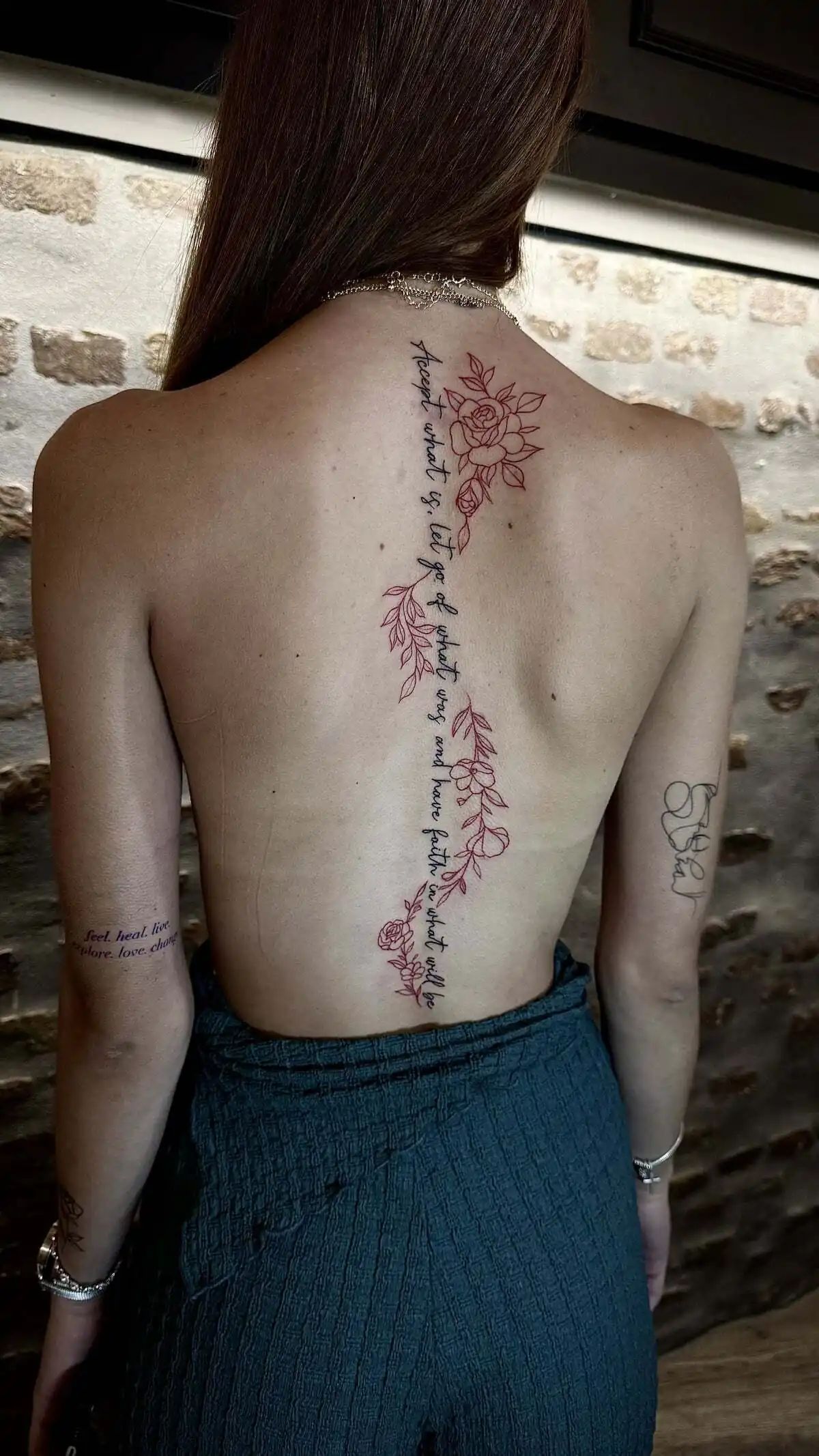 red fine line floral spine lettering tattoo
